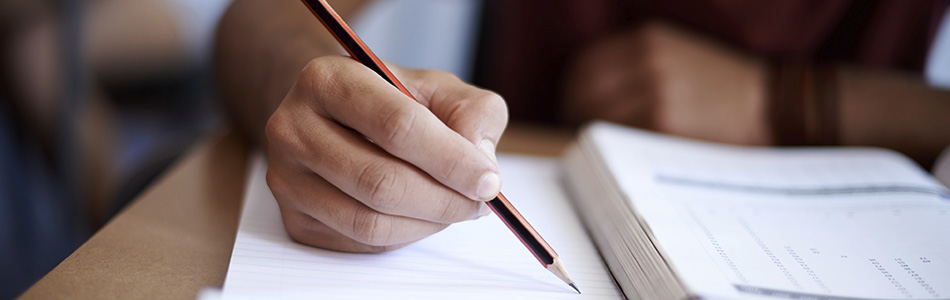 Una mano escribiendo con un lápiz en un cuaderno